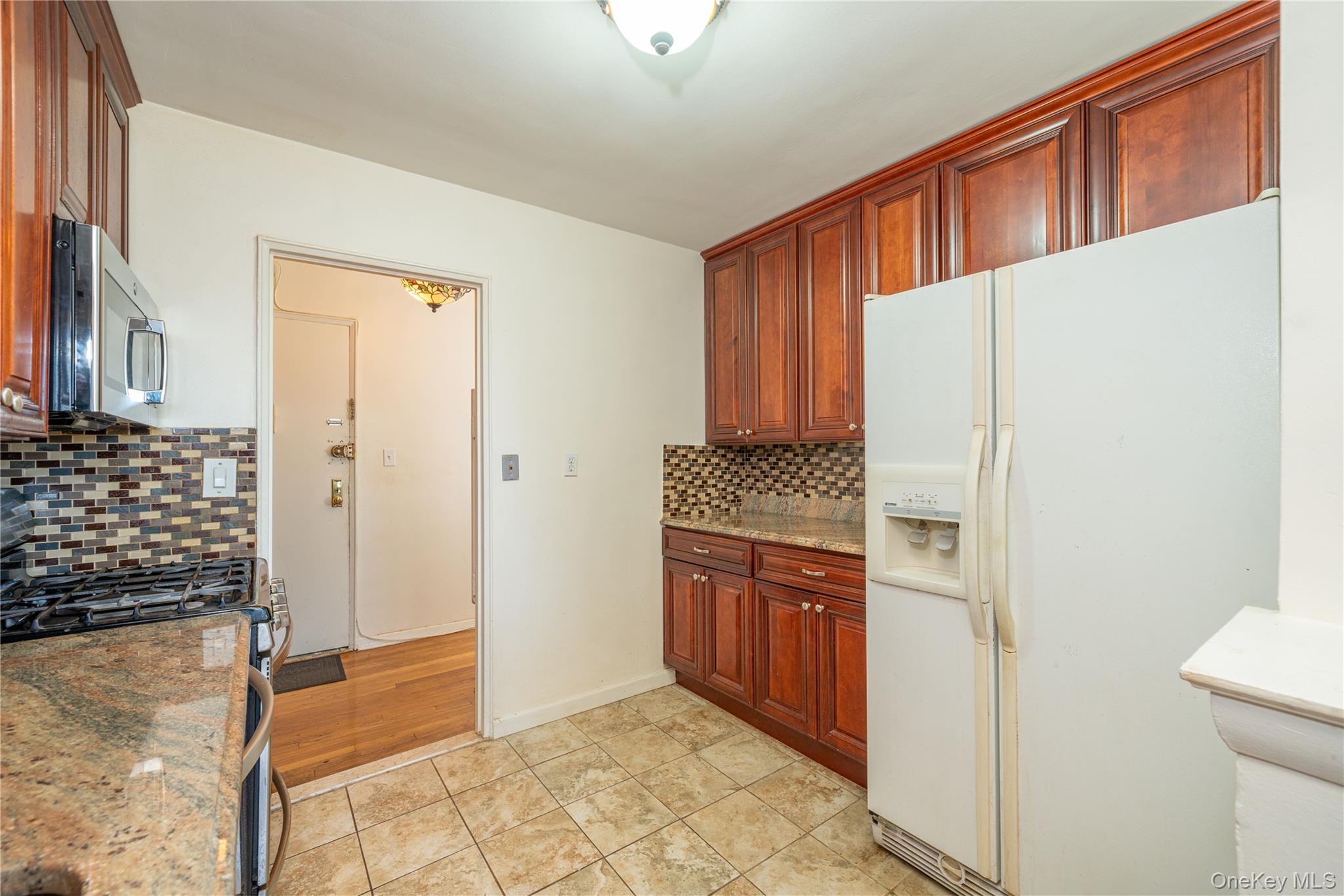 495 Odell Avenue, Unit 8R Yonkers, NY 10703 - Photo 11 of 27 Kitchen featuring stainless steel appliances, light stone counters, light tile patterned flooring, and tasteful backsplash