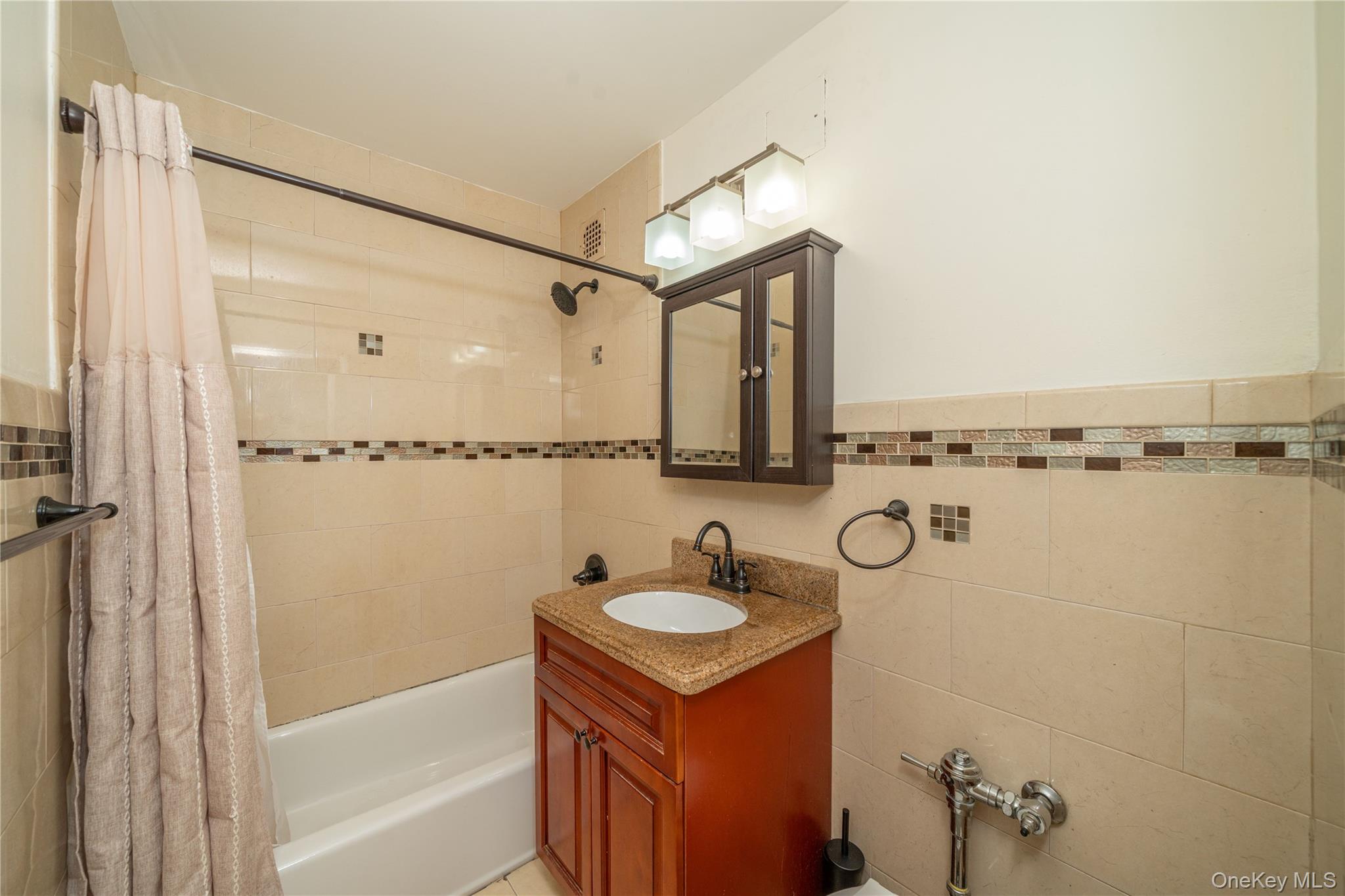 495 Odell Avenue, Unit 8R Yonkers, NY 10703 - Photo 19 of 27 Full bath featuring shower / bath combination with curtain, vanity, tile walls, and wainscoting