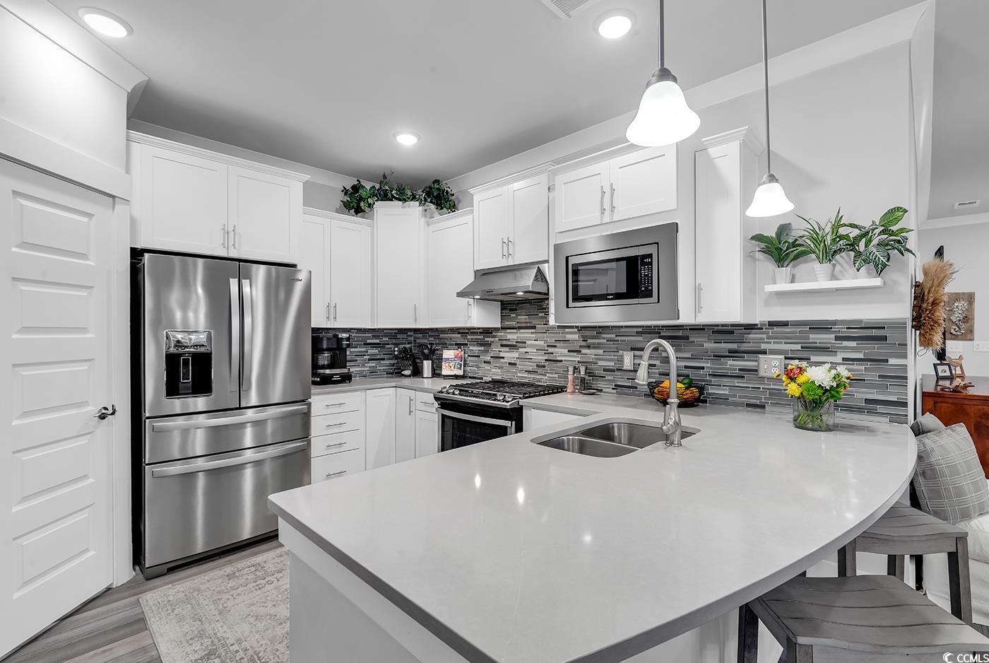6013 Tramonto Street Myrtle Beach, SC 29577 - Photo 14 of 40 Kitchen with a peninsula, stainless steel appliances, white cabinets, a breakfast bar area, and recessed lighting