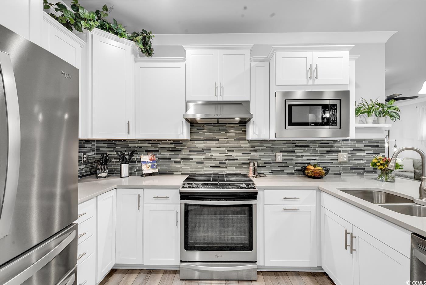 6013 Tramonto Street Myrtle Beach, SC 29577 - Photo 15 of 40 Kitchen with stainless steel appliances, white cabinets, and exhaust hood