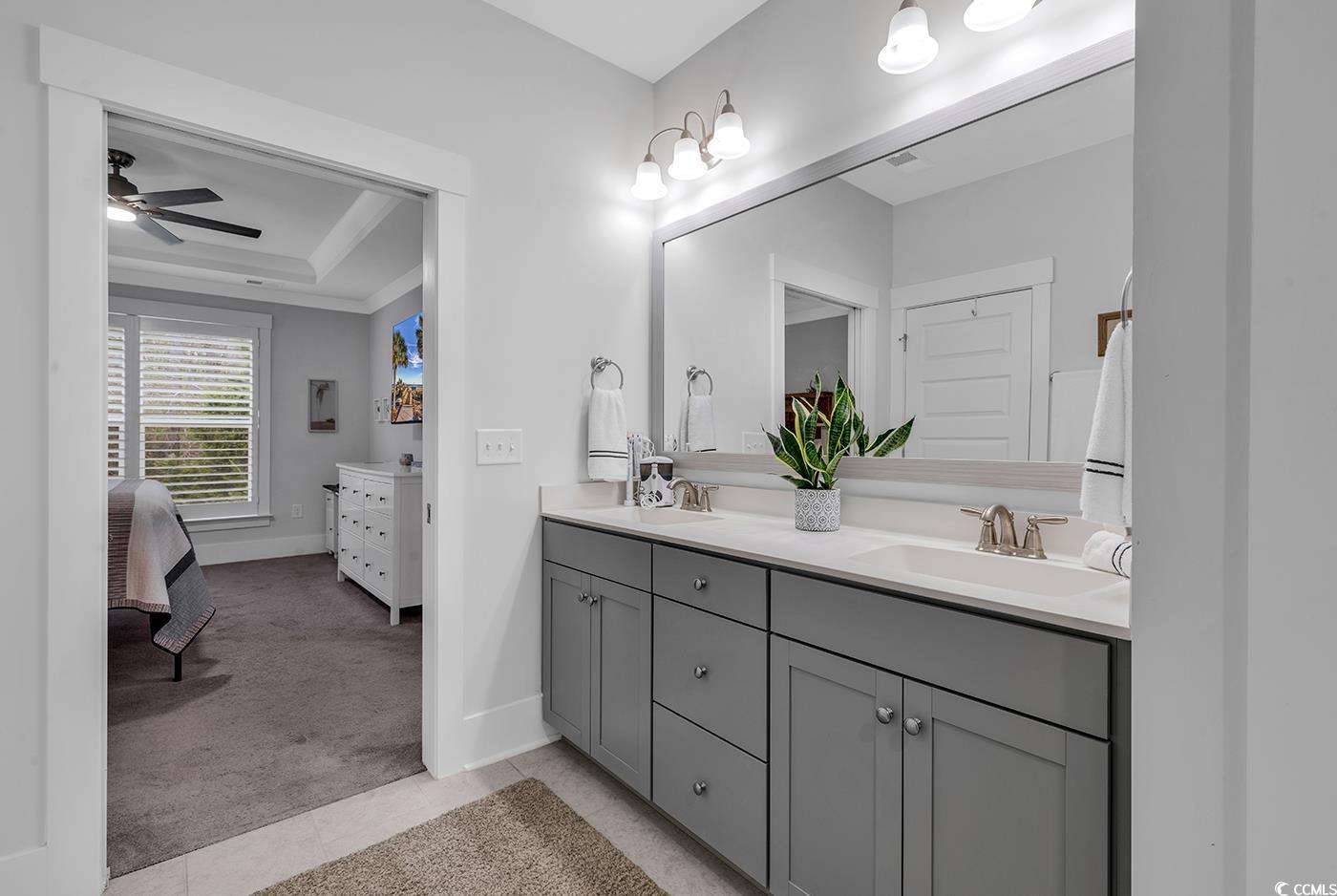 6013 Tramonto Street Myrtle Beach, SC 29577 - Photo 24 of 40 Ensuite bathroom featuring a tray ceiling, double vanity, light tile patterned flooring, ceiling fan, and ornamental molding