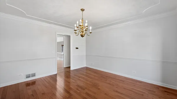 an empty room with wooden floor and chandelier