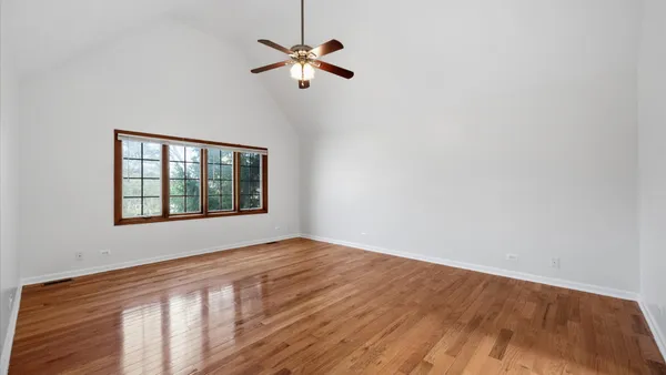 a view of a room with wooden floor a ceiling fan and wooden floor