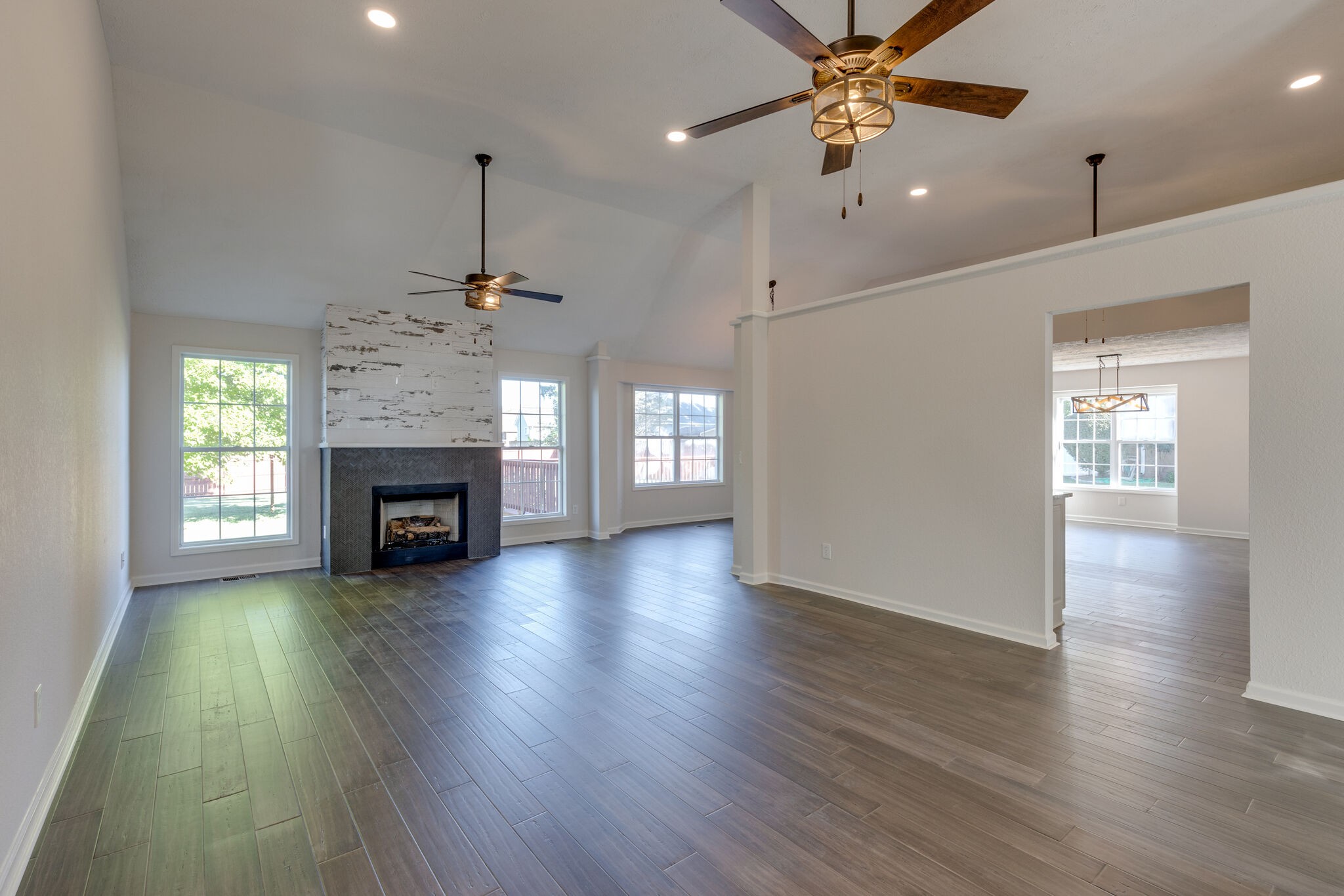 3648 Mahlon Moore Road Spring Hill, TN 37174 - Photo 7 of 30 an empty room with wooden floor a ceiling fan windows and a fireplace