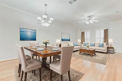 a kitchen with stainless steel appliances kitchen island granite countertop a sink a stove a dining table and chairs with wooden floor