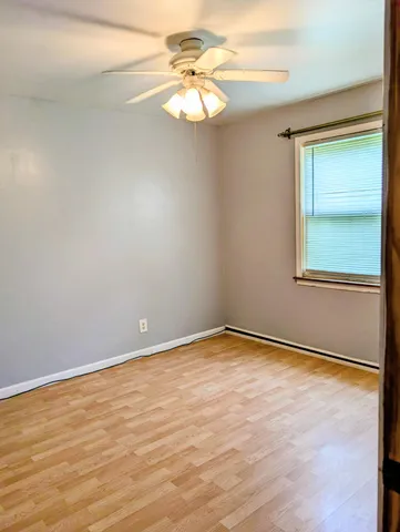 an empty room with a window and a fan