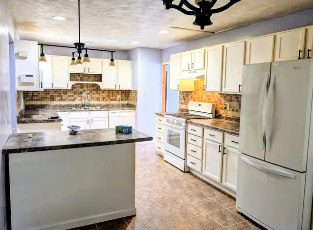 a kitchen with stainless steel appliances granite countertop a refrigerator a stove and a sink with wooden floor