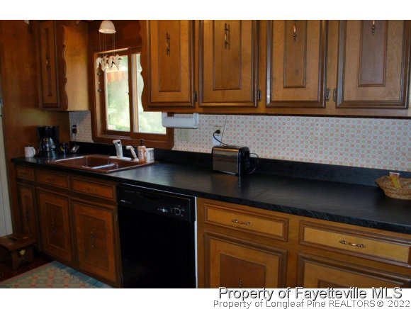 7371 Sherrill Baggett Road Dunn, NC 28334 - Photo 8 of 25 a kitchen with granite countertop a sink cabinets and black appliances