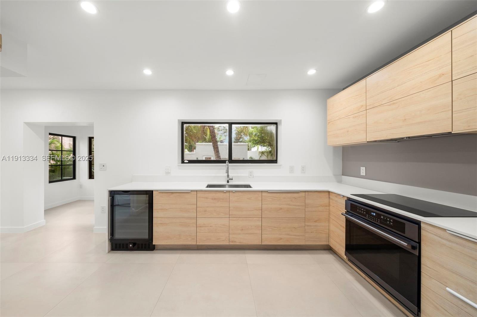 151 Northeast 43rd Street Miami, FL 33137 - Photo 29 of 51 a large white kitchen with a sink and dishwasher a stove top oven with wooden floor