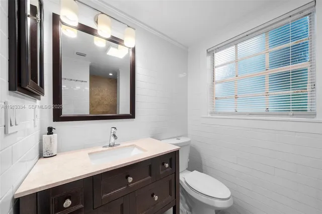 a bathroom with a granite countertop sink toilet a large mirror and a window