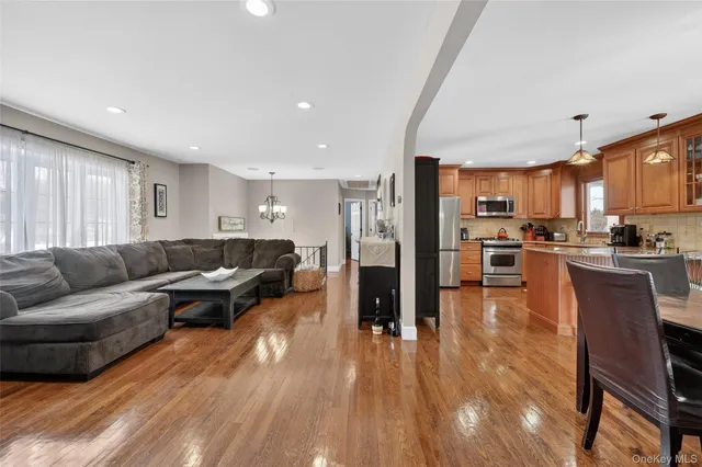 a living room with stainless steel appliances furniture and a wooden floor