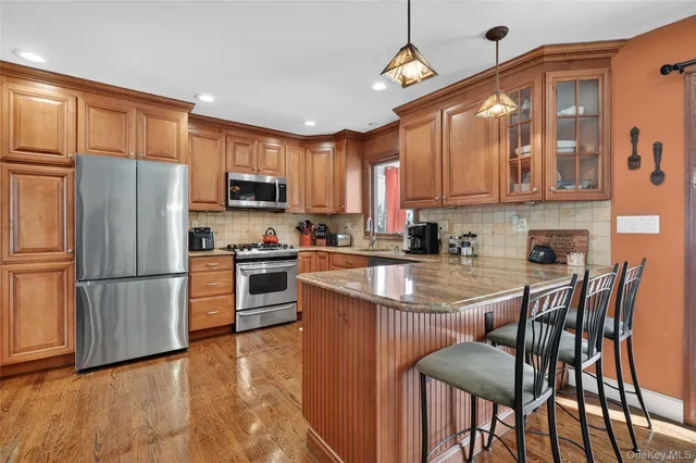 a kitchen with stainless steel appliances granite countertop a stove a refrigerator a sink a stove and white cabinets with wooden floor