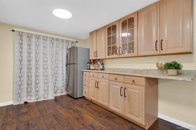 a kitchen with stainless steel appliances granite countertop a refrigerator a sink and white cabinets with wooden floor
