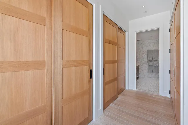 a view of a hallway with wooden floor and a bathroom