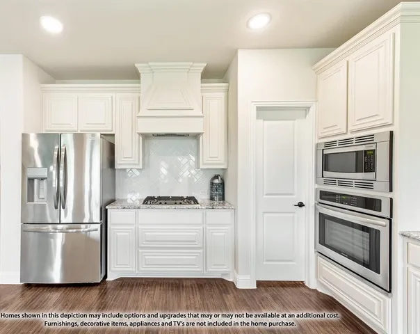 a kitchen with stainless steel appliances granite countertop a refrigerator a stove and white cabinets