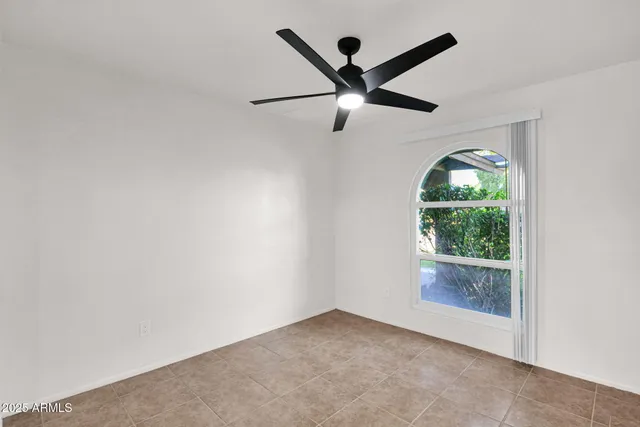 an empty room with windows and ceiling fan
