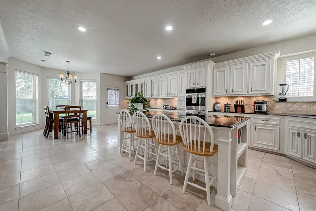 a kitchen with stainless steel appliances granite countertop a stove top oven a sink a dining table and chairs