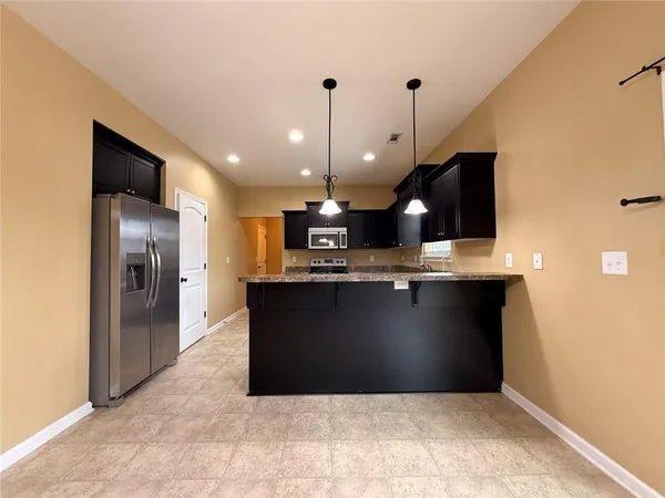 a view of a refrigerator in kitchen and an empty room