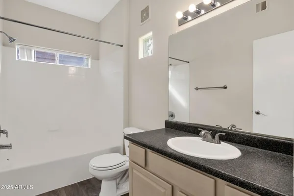 a bathroom with a granite countertop sink a toilet and a mirror