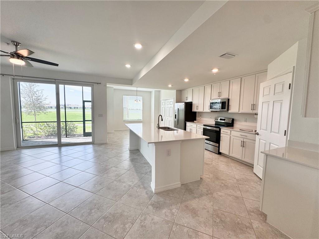 Kitchen with white cabinets, sink, an island with sink, and appliances with stainless steel finishes