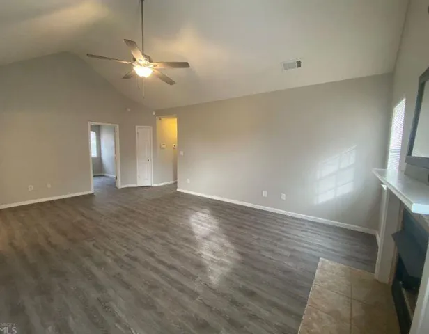 an empty room with wooden floor and chandelier fan