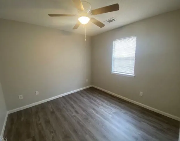 an empty room with a window and wooden floor
