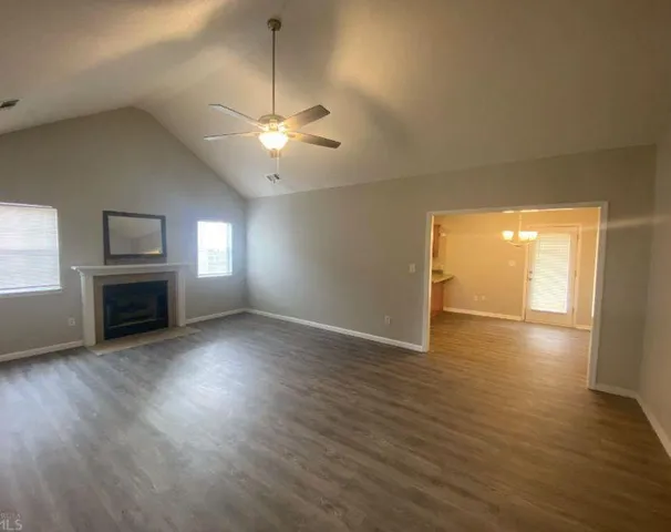 an empty room with wooden floor fireplace and windows