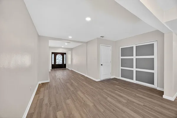a view of an empty room with wooden floor and a window