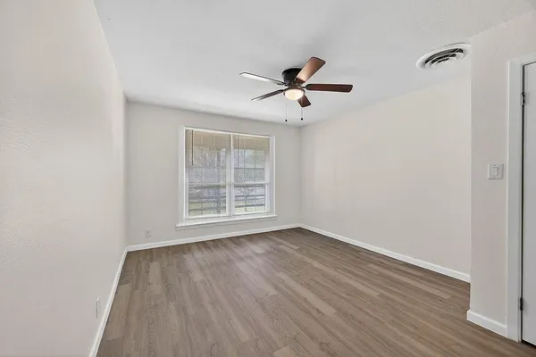 a view of empty room with wooden floor and fan