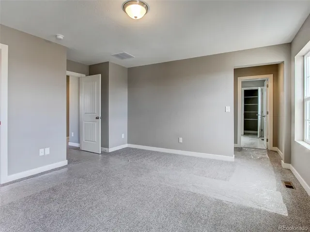a view of an empty room with closet and a window