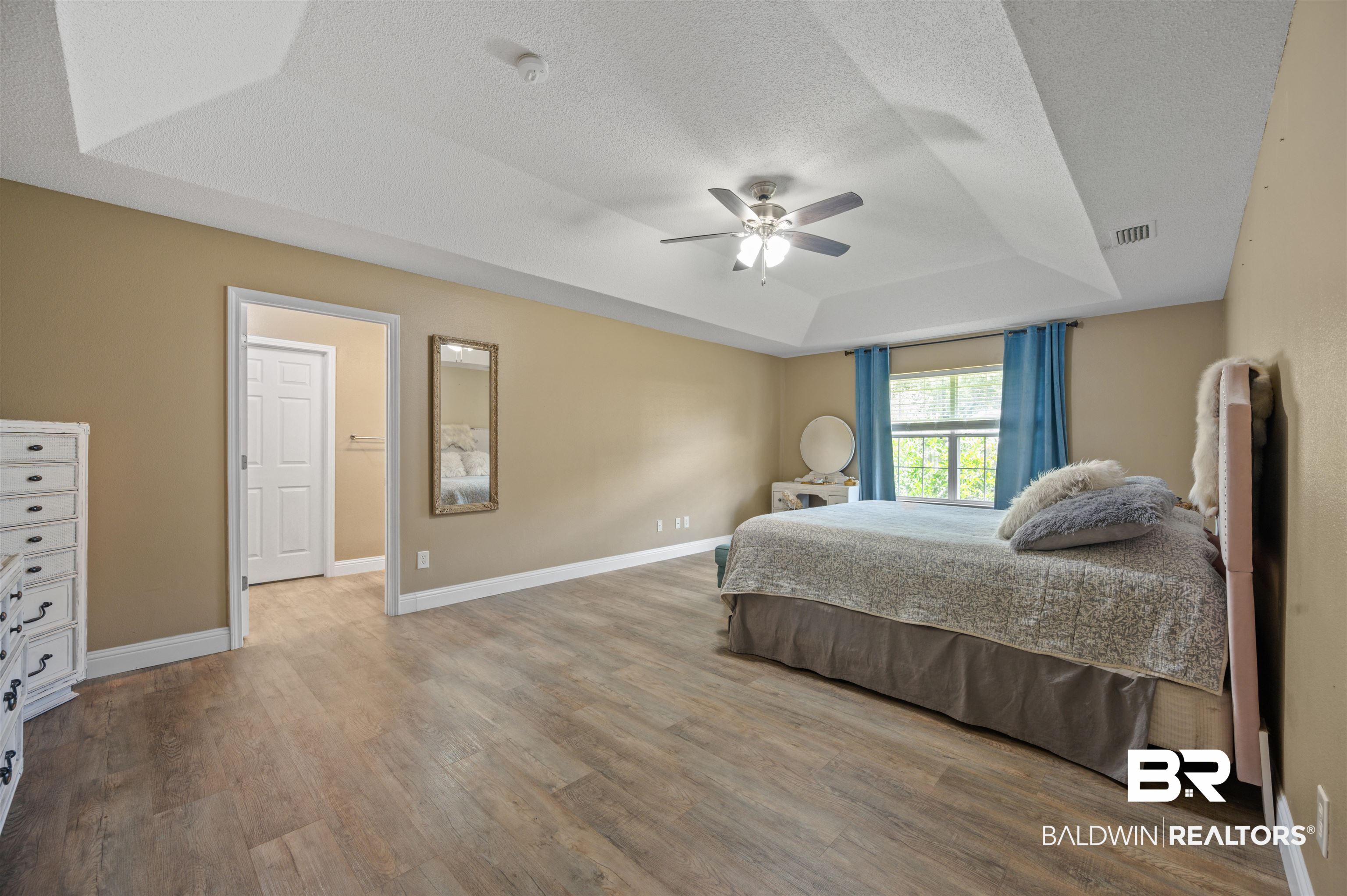 11705 Venice Boulevard Foley, AL 36535 - Photo 22 of 43 Bedroom featuring a tray ceiling, hardwood / wood-style flooring, ceiling fan, and a textured ceiling