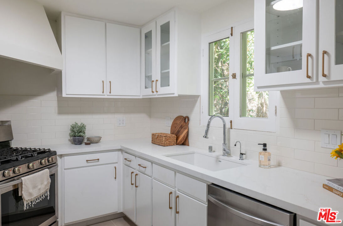 488 St Pierre Road Los Angeles, CA 90077 - Photo 5 of 12 a kitchen with a sink dishwasher a stove and white cabinets next to a window