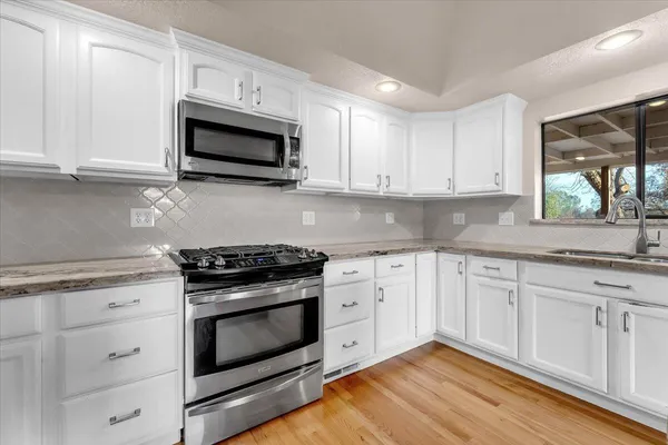 a kitchen with granite countertop a sink a stove and cabinets