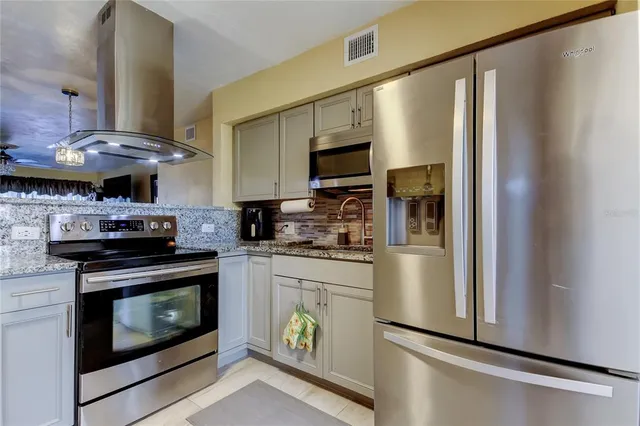 a kitchen with stainless steel appliances granite countertop a refrigerator a stove and a sink with wooden floor