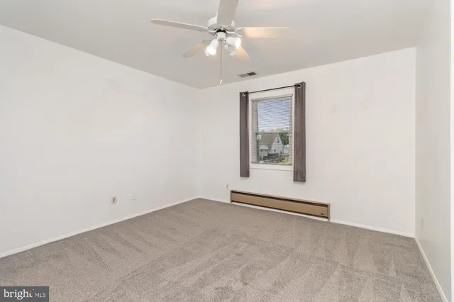 an empty room with a window and ceiling fan