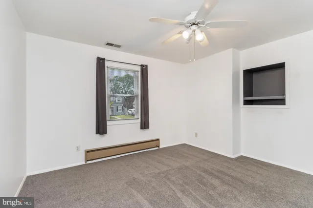 a view of an empty room with window and a ceiling fan