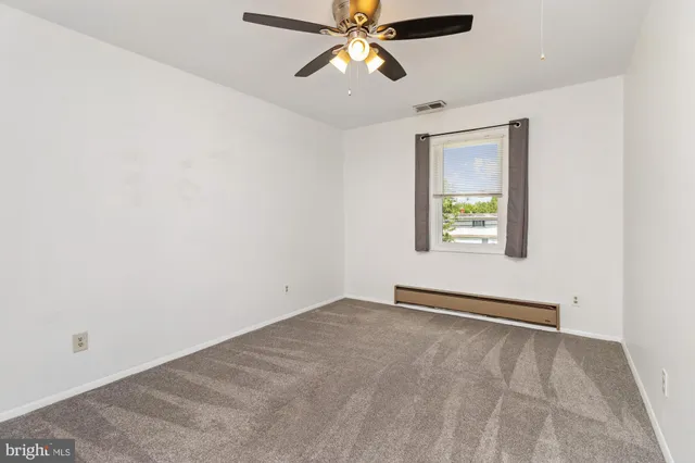 an empty room with windows and fan