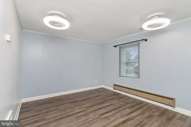 a view of an empty room with a window and wooden floor