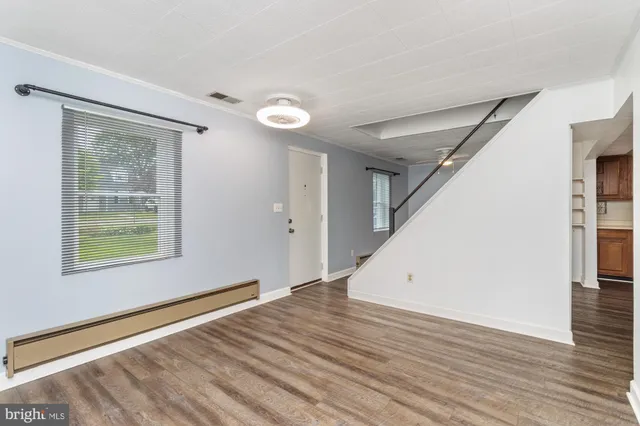 a view of an empty room with wooden floor and a window