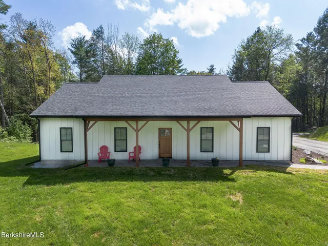 a front view of house with yard and trees in the background