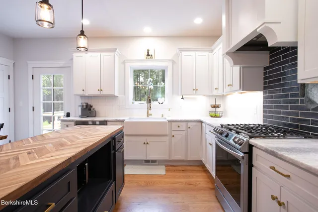 a kitchen with stainless steel appliances granite countertop a sink stove and cabinets