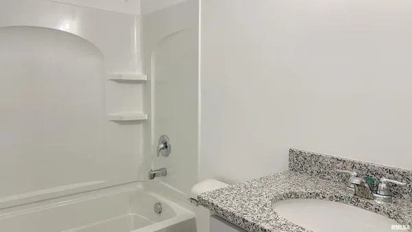 a bathroom with a granite countertop sink and a bathtub
