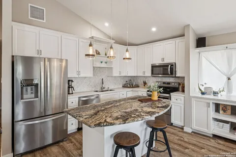 a kitchen with kitchen island a refrigerator stove and white cabinets