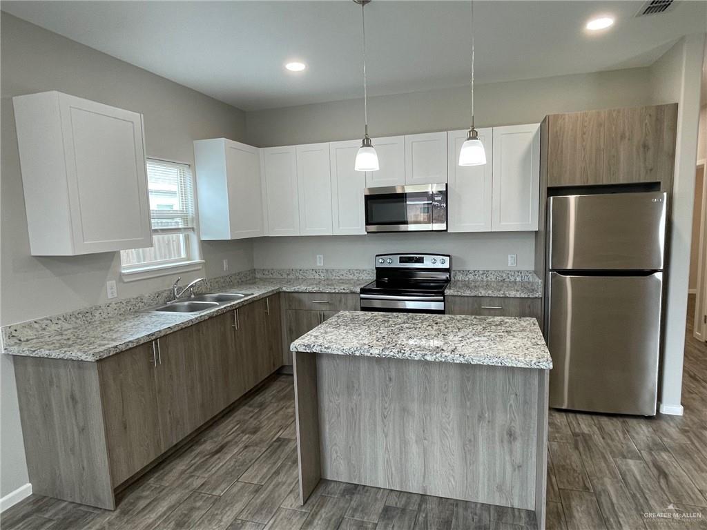 912 Kentucky Street Alton, TX 78573 - Photo 14 of 21 a kitchen with stainless steel appliances granite countertop a refrigerator a sink dishwasher a stove top oven a refrigerator and white cabinets