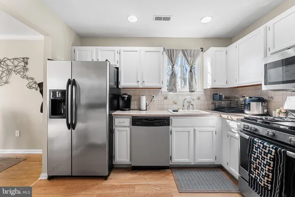 a kitchen with stainless steel appliances a refrigerator sink and white cabinets