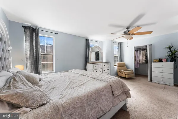 a spacious bedroom with a bed a dresser and a chandelier