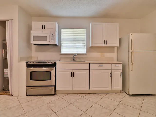 a kitchen with white cabinets and white appliances
