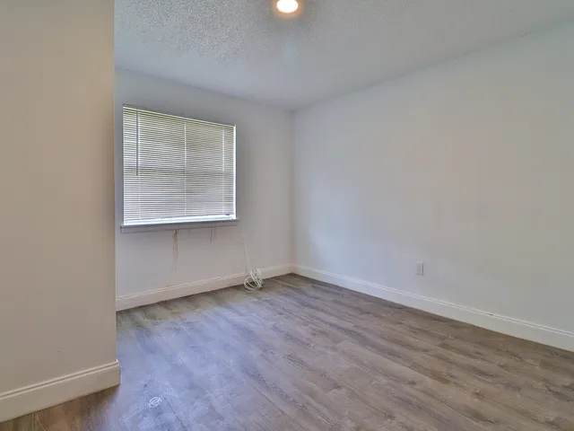 an empty room with wooden floor and a window