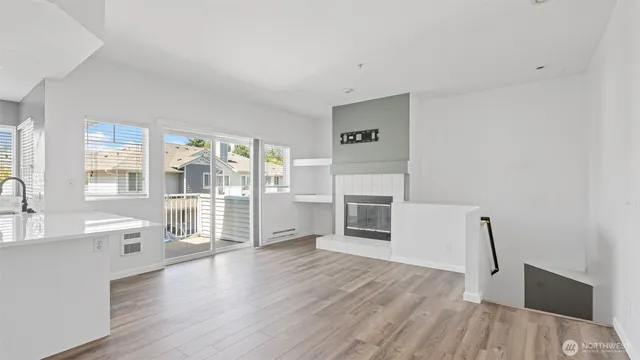 a living room with stainless steel appliances furniture a large window and wooden floor