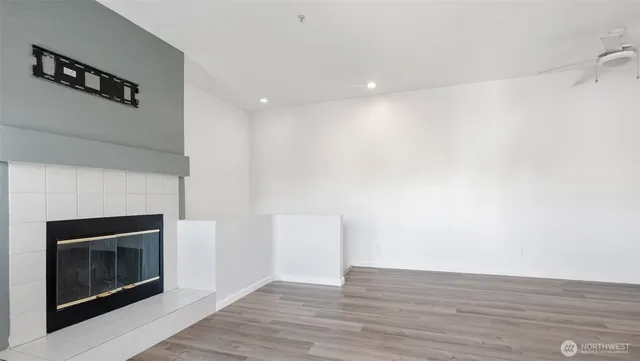 a view of an empty room with wooden floor and a fireplace